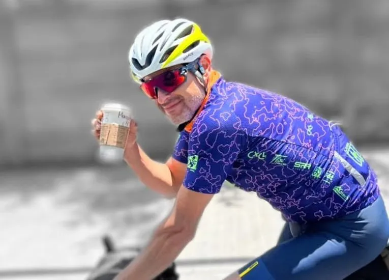 Marcelo, de Mundobikes, levantando un café para llevar mientras pedalea en su bici de ruta