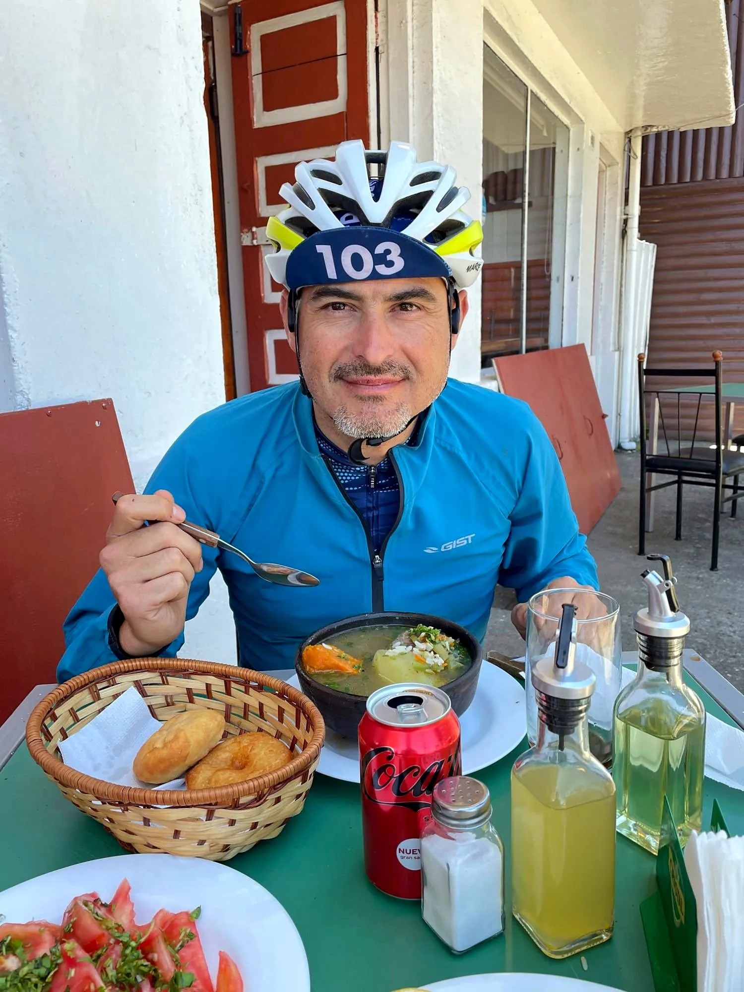 Ciclista con casco comiendo una cazuela con pan y tomates después de una salida