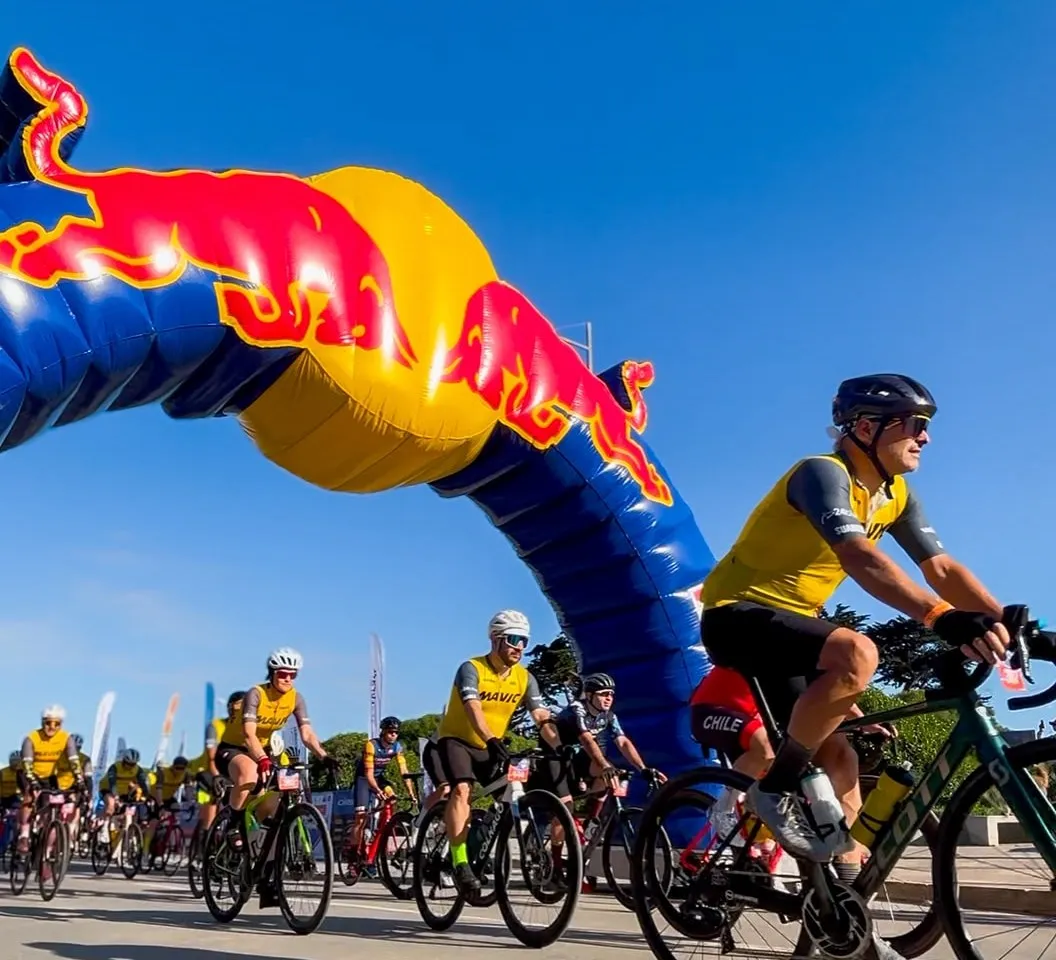 Largada del Gran Fondo Matanzas bajo un arco inflable, con un grupo de ciclistas de ruta con jerseys amarillos saliendo detrás