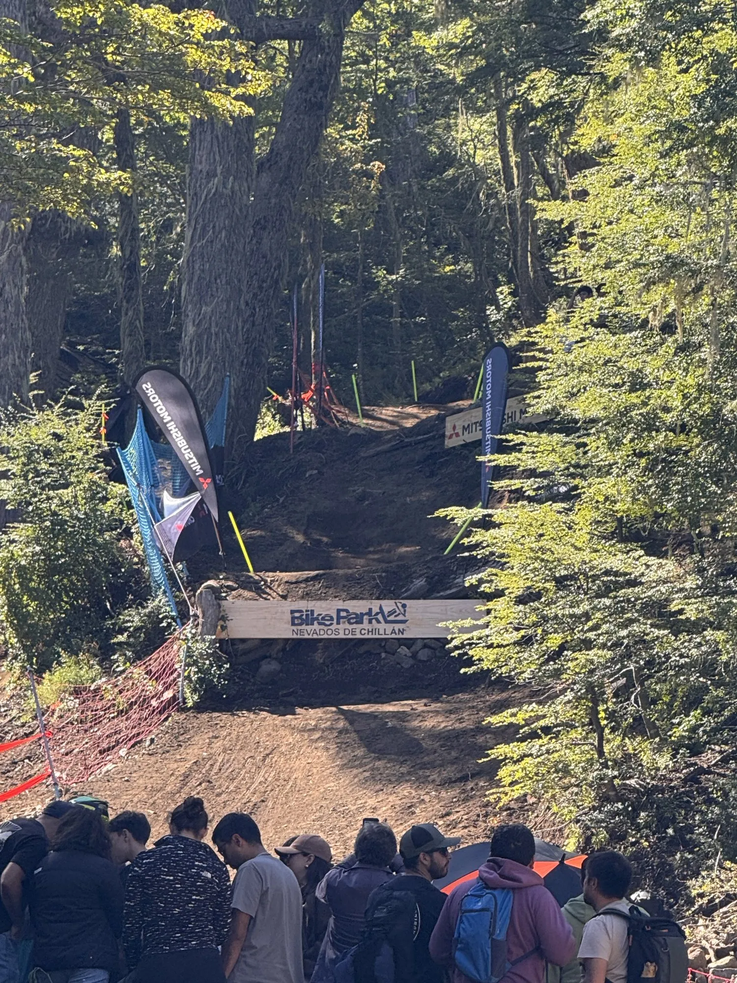 Público junto a la pista de descenso del Bike Park Nevados de Chillán, con un salto entre árboles nativos, durante el Mundial Masters 2026