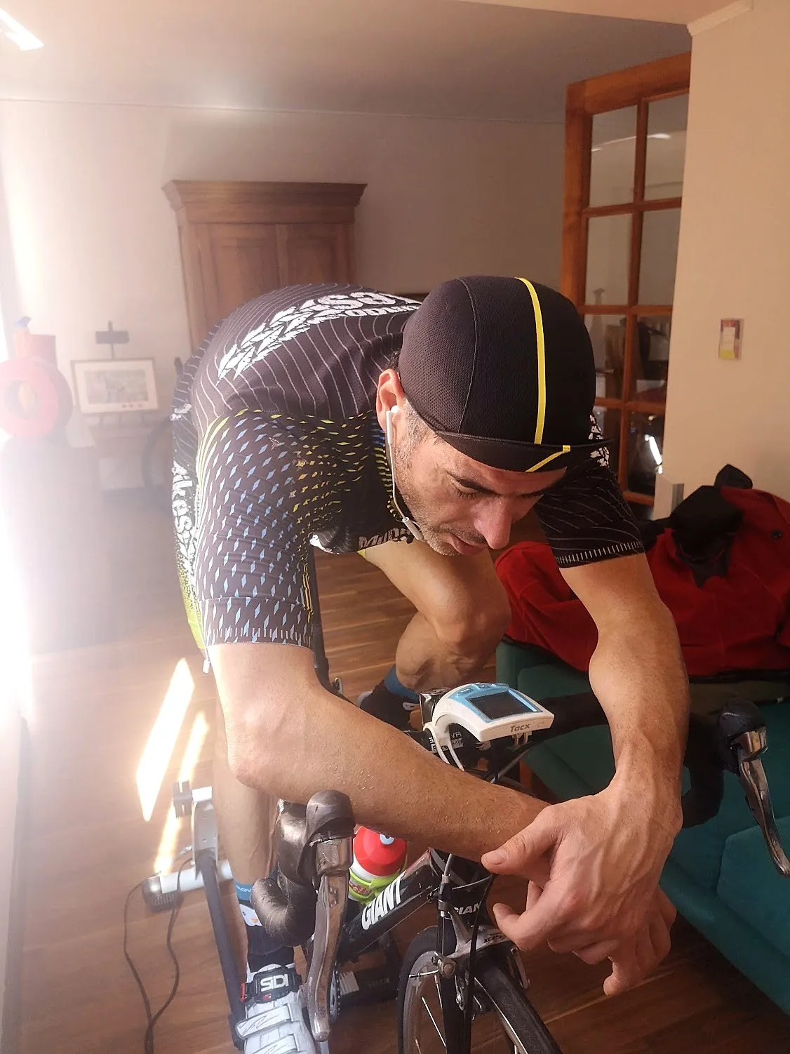 Ciclista entrenando en un rodillo en casa, con el ciclocomputador del rodillo montado en el manubrio